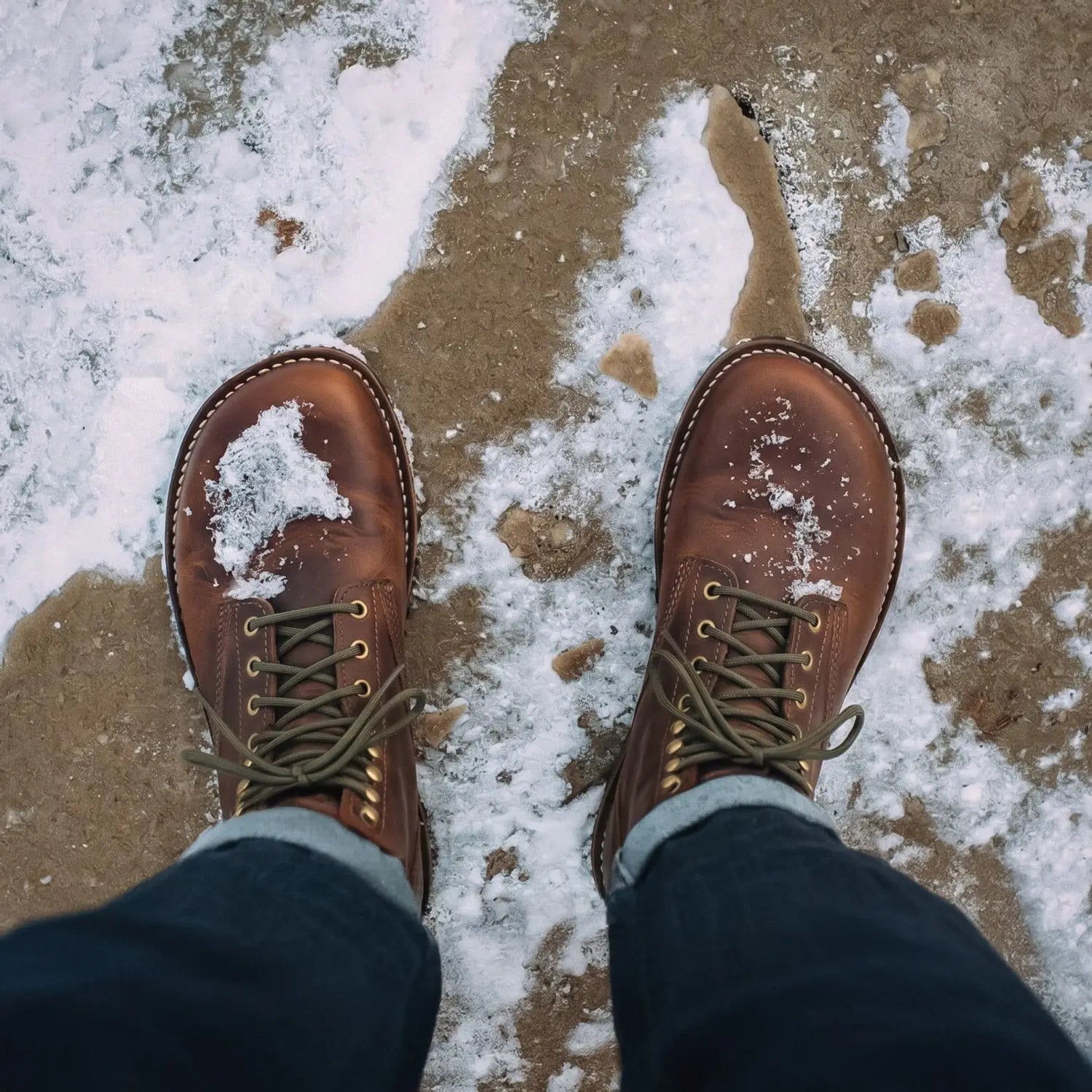 ArktOS cognac brown leather winter-ready barefoot boot in full-grain bison leather with olive laces dusted with snow