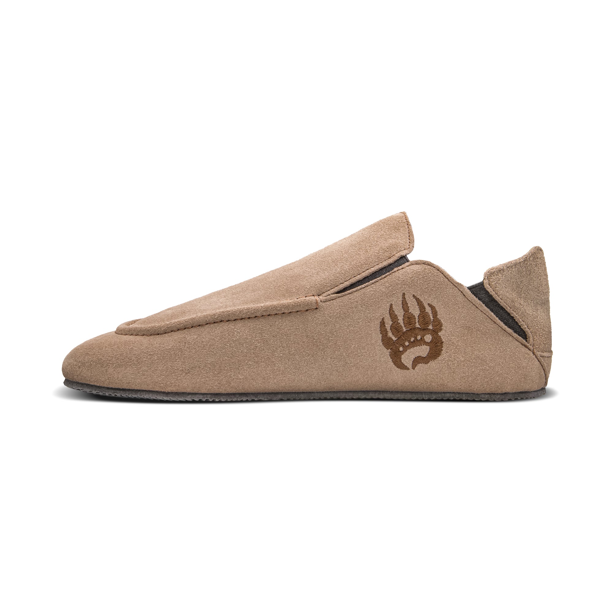 A side view of a Oso Suede slipper with a minimalist design, featuring a dark logo resembling a bear paw near the heel and made from suede leather for a barefoot experience. (Brand Name: Bearfoot)