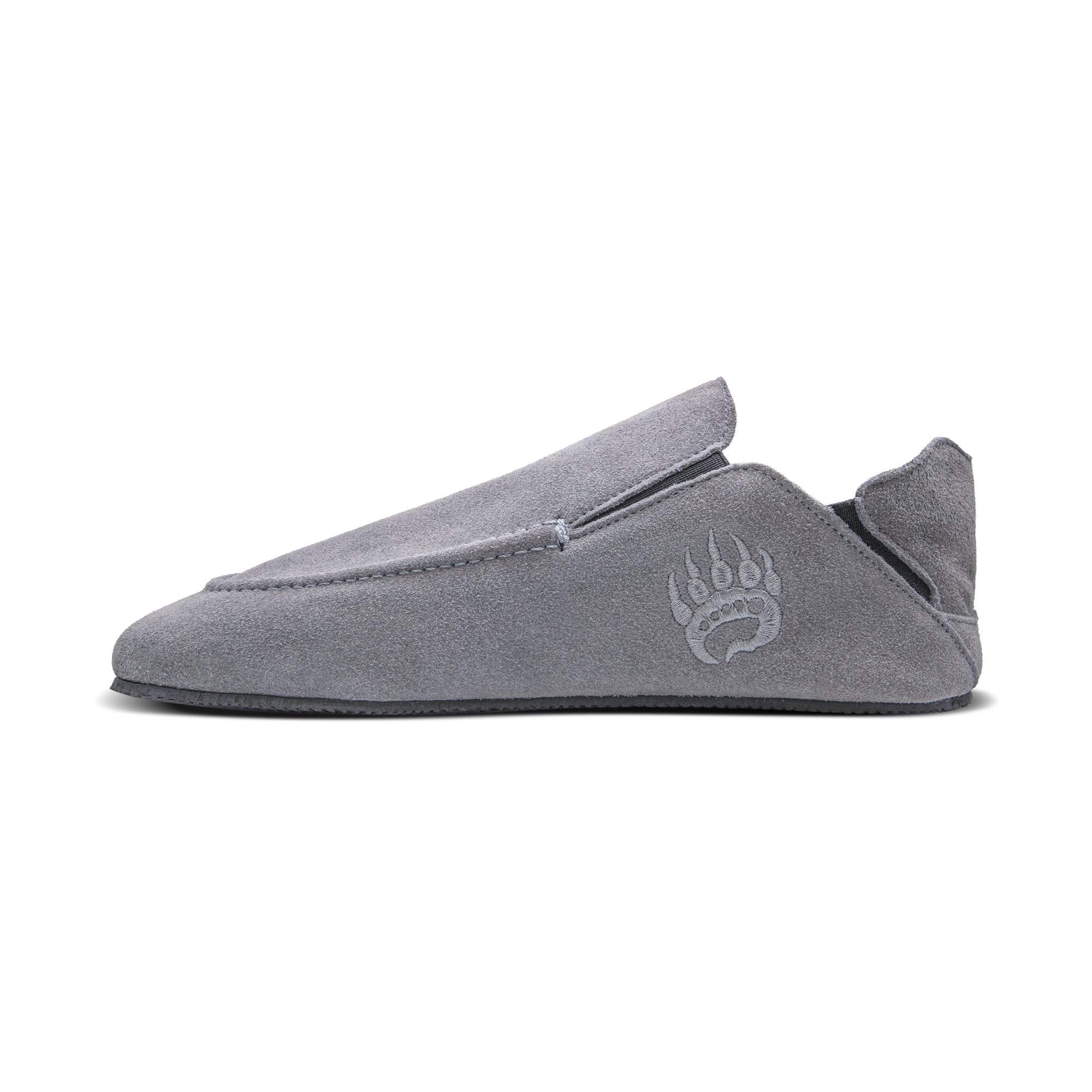 A single Oso Suede slipper in Ice Grey with a white paw print logo on the side, made from suede leather, offers a barefoot experience. The slipper features a low back and a round toe design. Brand Name: Bearfoot
