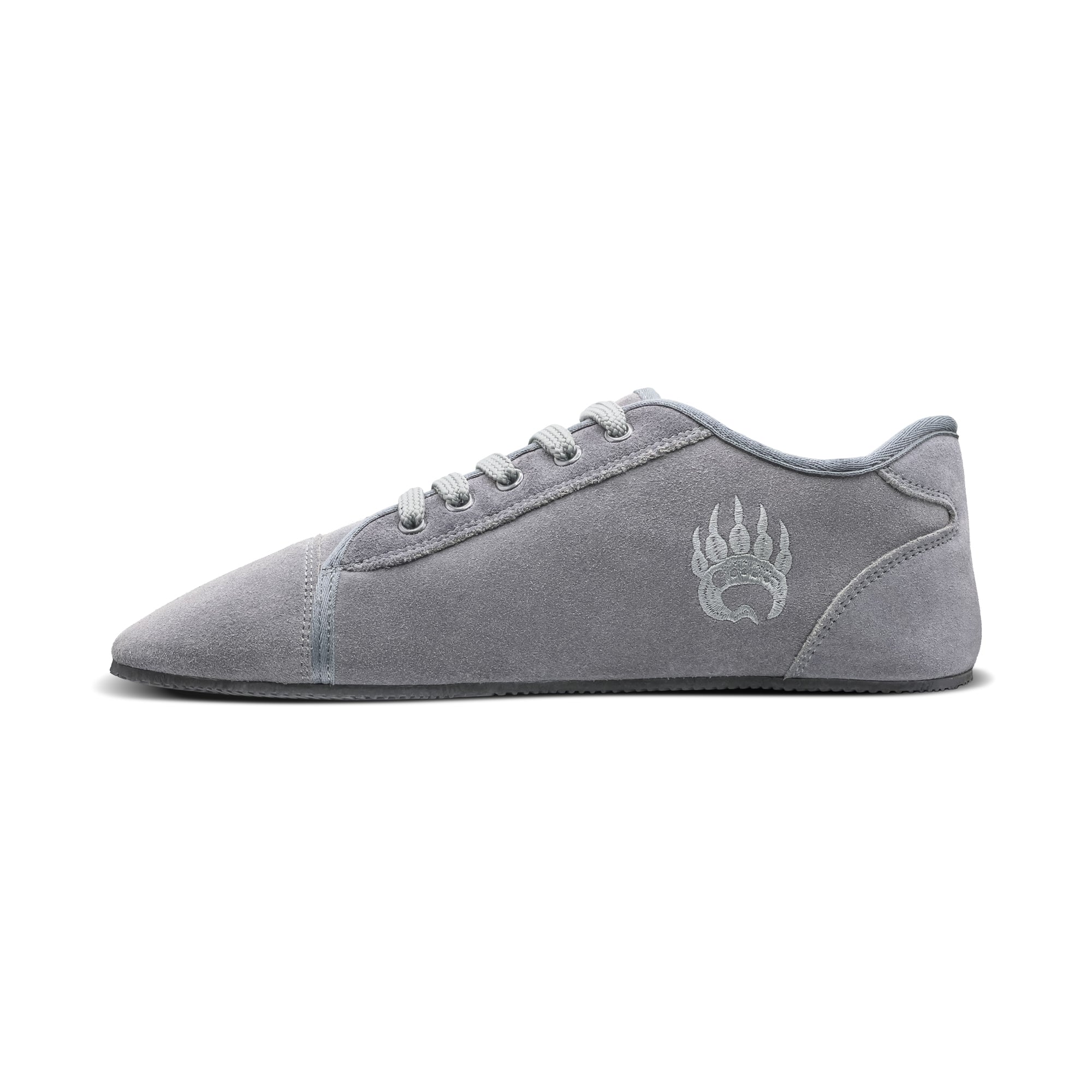 A profile view of a Bearfoot Ursus Suede Low-Top Ice Grey sneaker with a darker grey logo on the side, featuring a minimalist design and flat sole, laced up with white laces.
