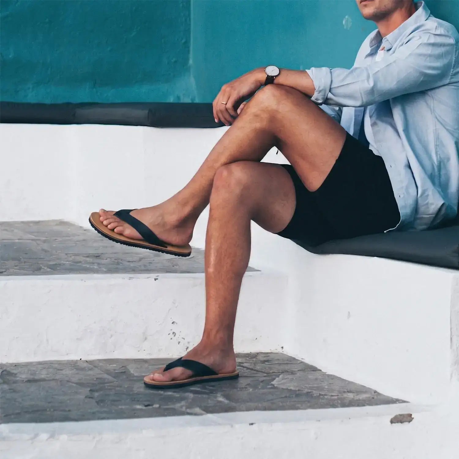 Black flip-flops with a simple, minimalist design and tan rubber soles.