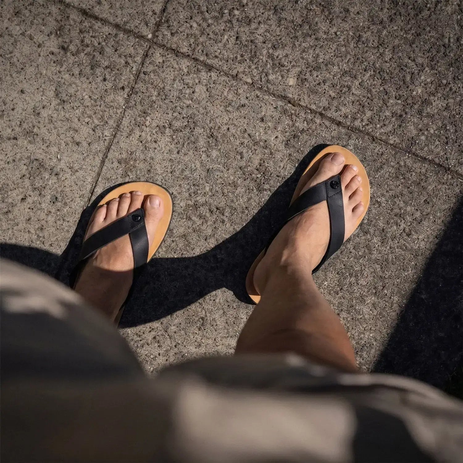 Black leather thong sandals with tan rubber soles.