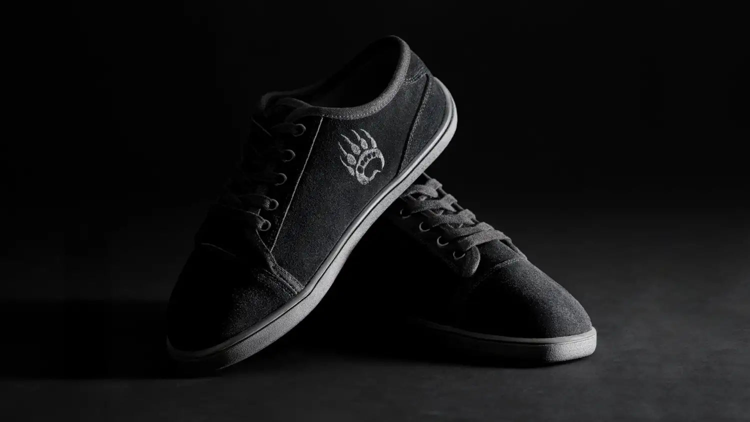 Black suede skate shoe with a white paw print logo on the side.
