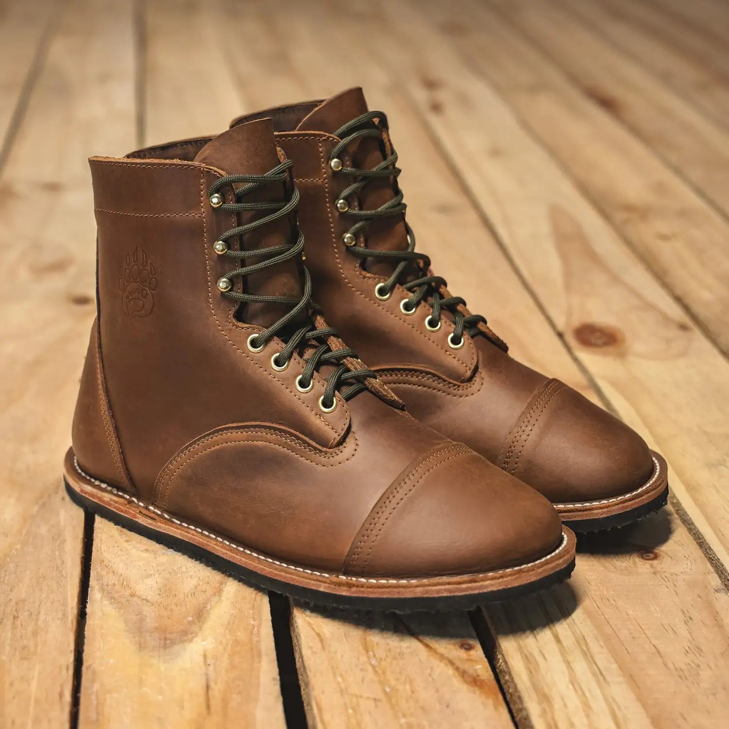 Brown leather work boots with dark green laces and silver eyelets.